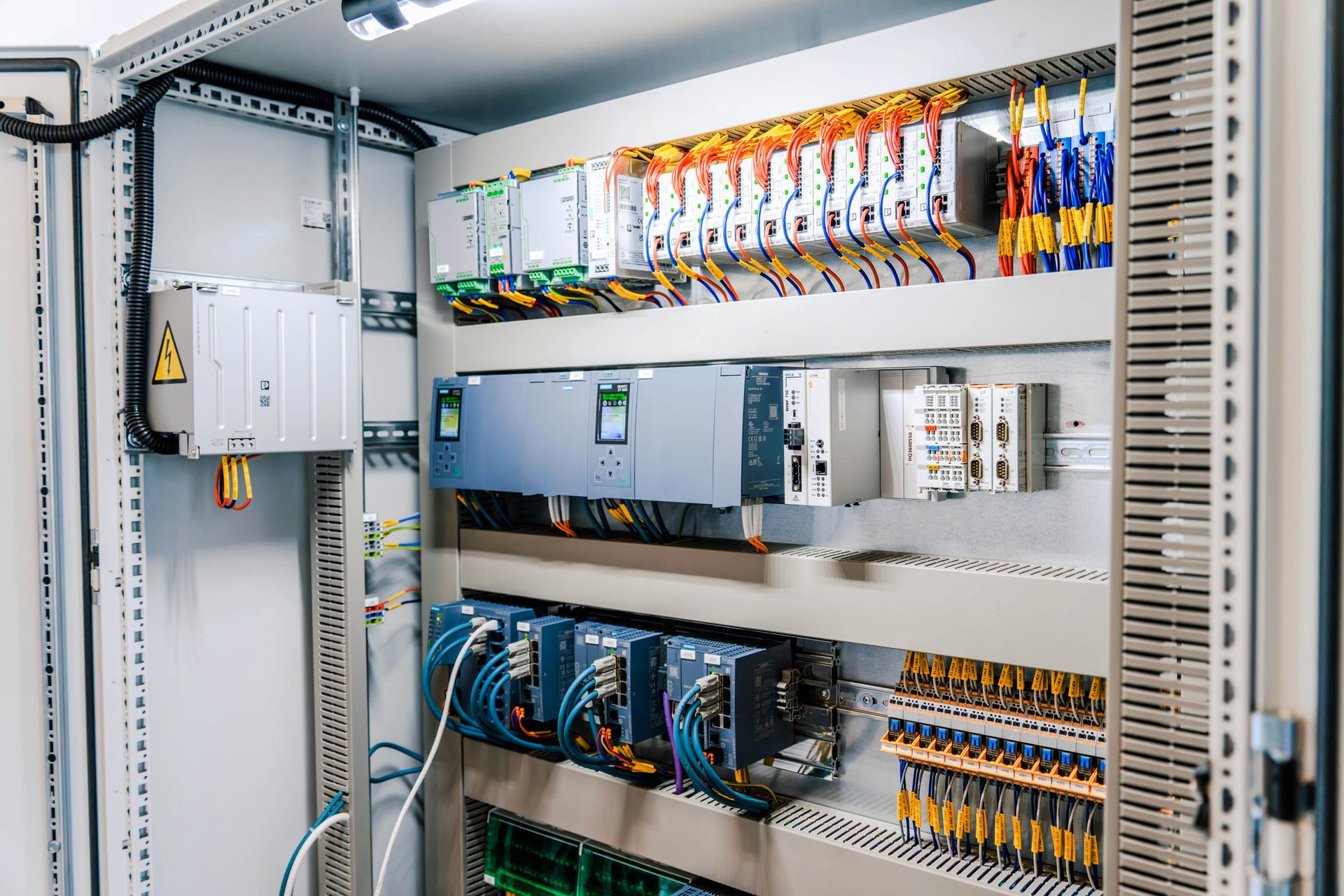 Open industrial electrical control panel with wires and modules